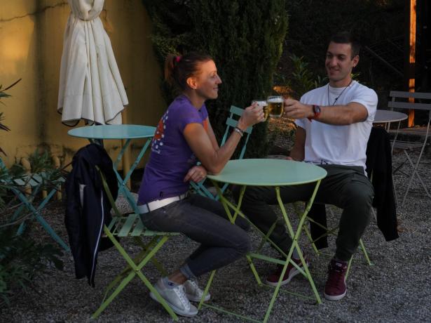 Two people toast outdoors with beer glasses.