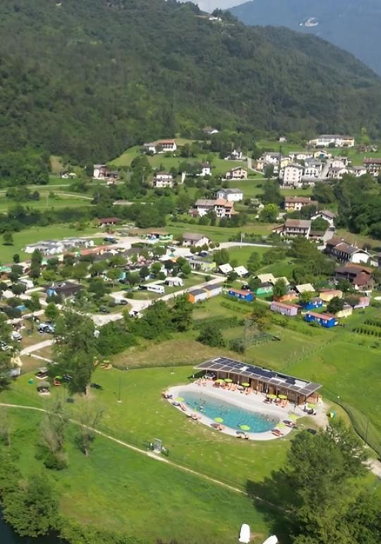 Aerial view of a green campsite with a pool nestled in the mountains.