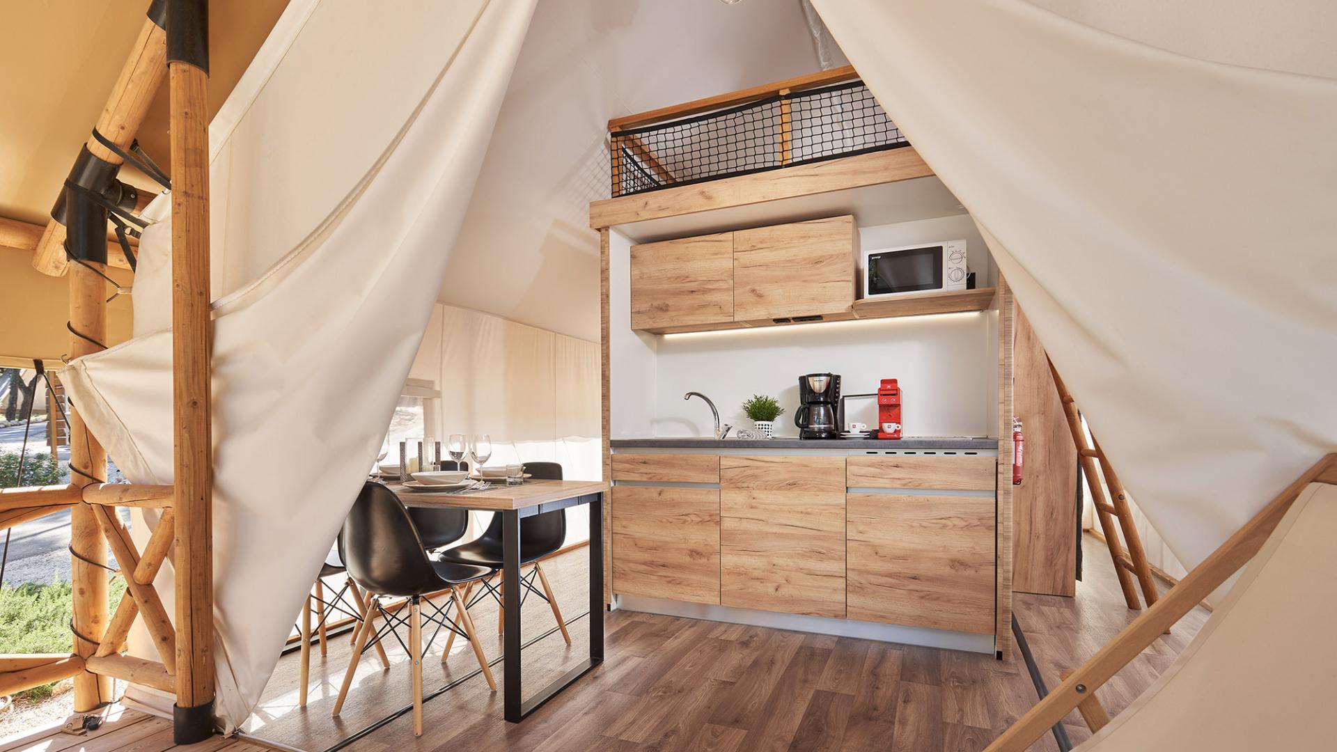 Modern kitchen in a glamping tent with dining table.