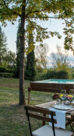 Set table outdoors near a pool in a tree-filled garden.