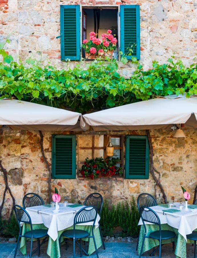 Restaurant extérieur accueillant avec des tables dressées et des fleurs colorées.