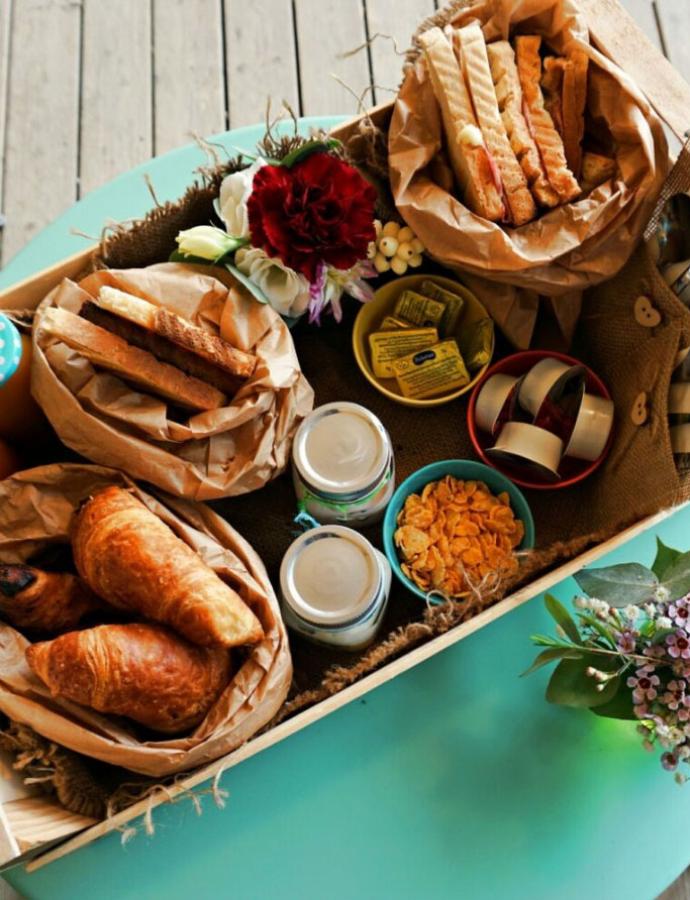 Breakfast with croissants, bread, cereals, yogurt, and fresh flowers.