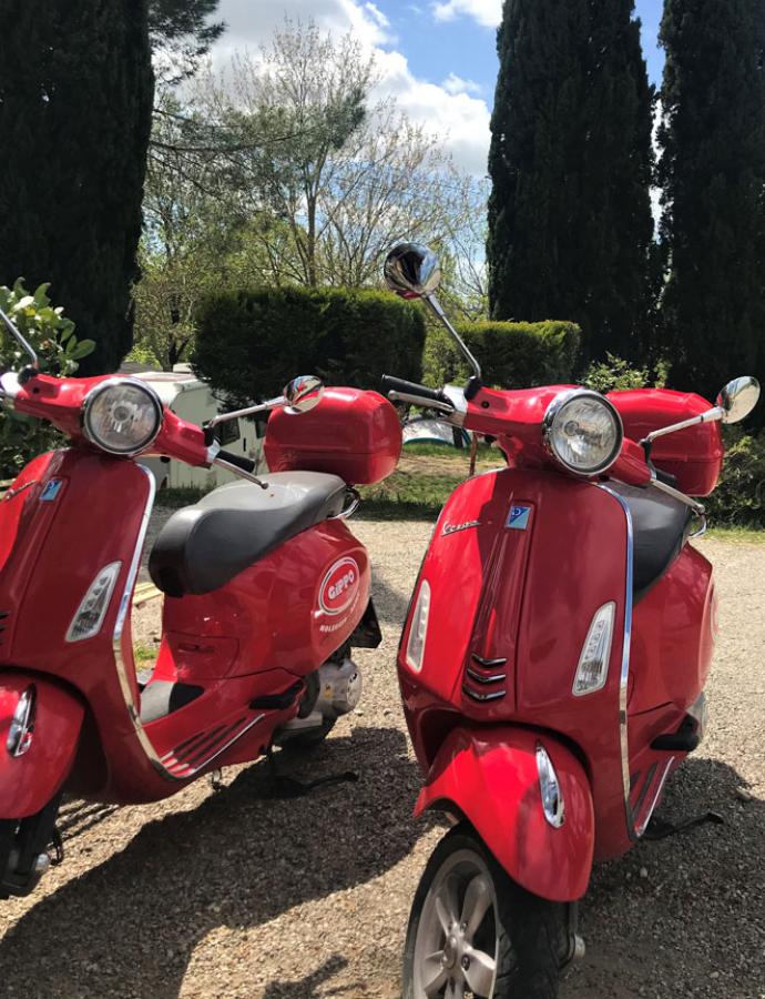 Two red Vespas parked outdoors on a sunny day.