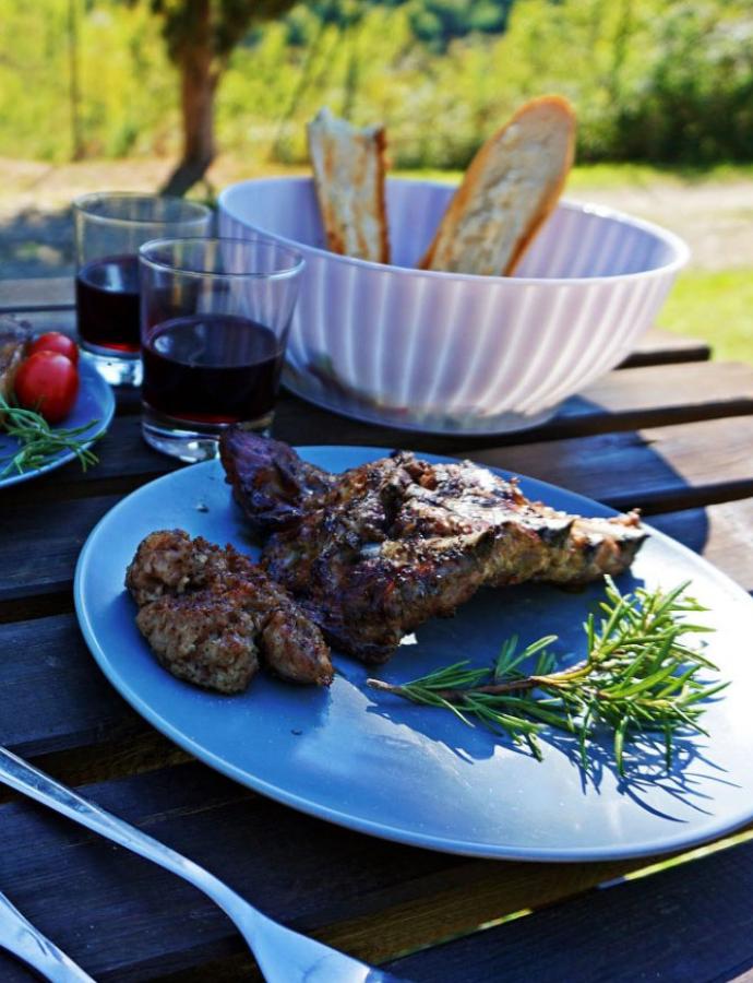 Grilled meat with red wine and bread outdoors.