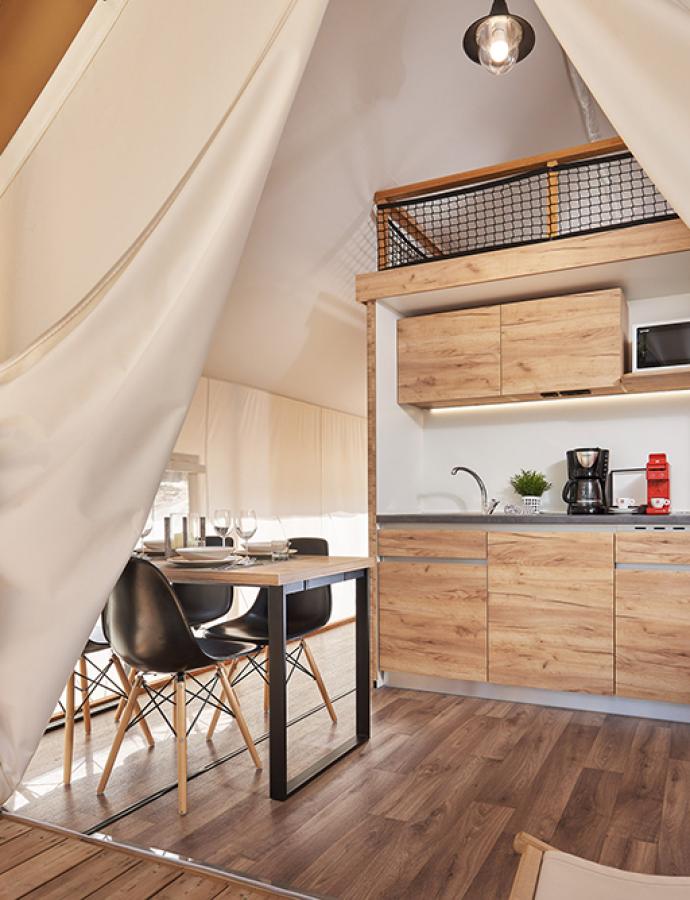 Interior of a glamping tent with kitchen and dining area.