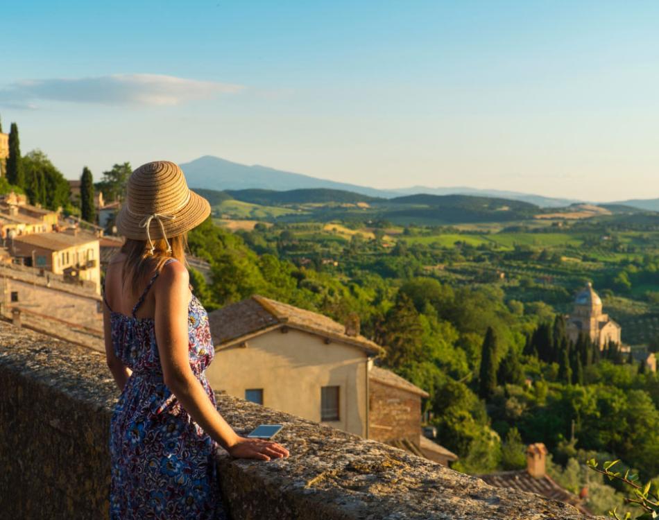 Donna con cappello ammira il paesaggio collinare da un punto panoramico.